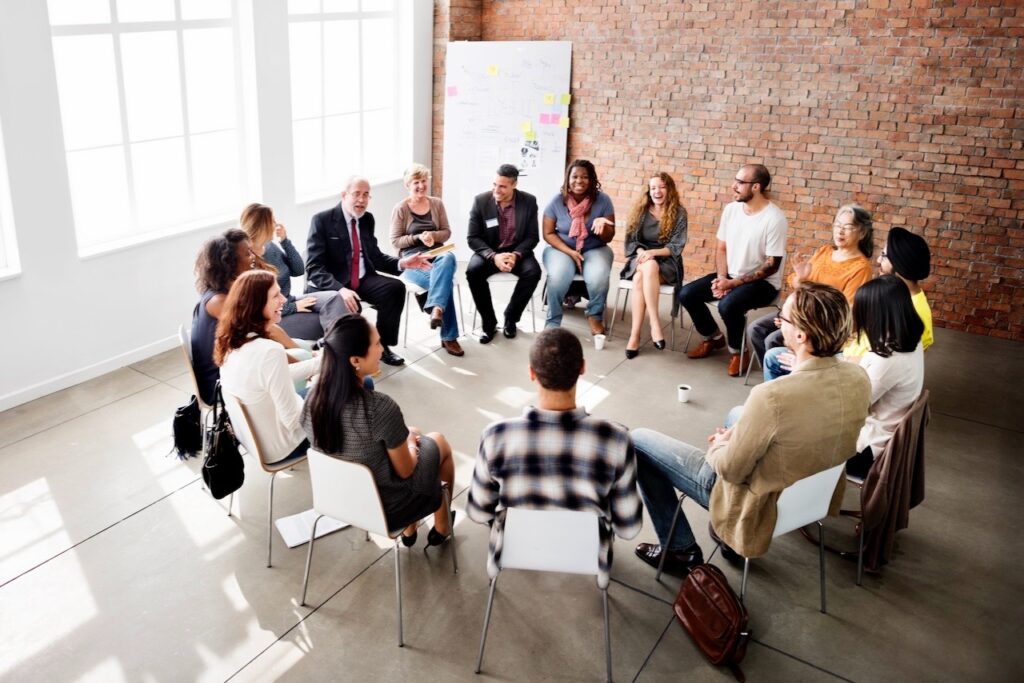 Stuhlreis mit Gruppe von Menschen als Bild für Organisationsentwicklung